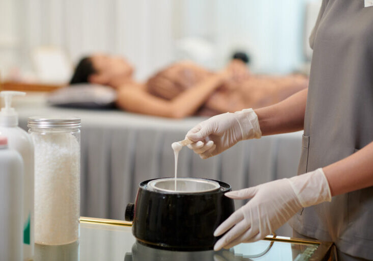 Hands of beautician melting wax for hair removal procedure